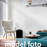 Ein Wohnzimmer mit blauem Sofa, gemusterter Sessel und runder Tisch.