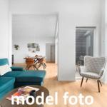 Wohnzimmer mit Sofa, Sessel und Essbereich. Holzboden und große Fenster.