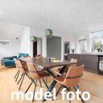 Essbereich mit Holztisch, Lederstühlen und Kücheninsel mit Kühlschrank.