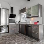 Moderne Küche mit Edelstahl-Kühlschrank und dunklen Schränken.