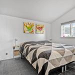 Schlafzimmer mit Bett, Fenster und zwei Wandbildern.