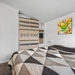 Schlafzimmer mit Bett, Kleiderschrank und Wandbildern.
