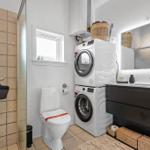 Badezimmer mit Dusche, Toilette, Waschmaschine und Spiegelschrank.