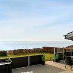 Terrasse mit Blick auf das Meer und grünen Rasenbereich.
