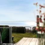 Terrasse mit Blick auf ruhiges Wasser und grünen Rasenbereich.