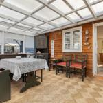 Terrassenbereich mit Tisch, Stühlen und Holzwand. Durchgang zu Wohnraum.