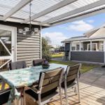 Terrasse mit Tisch, Stühlen und Sonnenschutz. Hintergrund zeigt Wohnhaus mit Fenstern.