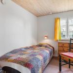 Ein Schlafzimmer mit Bett, Schrank, Stuhl und Fenster mit gelben Vorhängen.