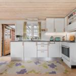 Küche mit weißen Schränken, Holzdecke und gemustertem Teppich.