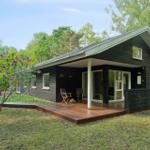 Moderne Holzhütte mit Terrasse und Garten. Holzveranda mit zwei Stühlen.