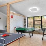 Room with ping pong table, foosball table, and desk. Wooden floor and large windows.