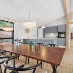 Dining area with table, chairs, and kitchen area in the background.