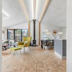 Living and dining area with wooden floor, fireplace, and seating.