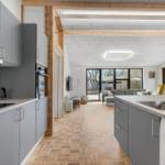 Kitchen with countertop and dining area with sofa and windows.
