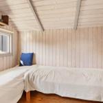 A bedroom with wooden walls, bed, and window.