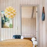 Dining area with round table and white chairs. Behind door is sleeping area with mattress.