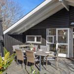 Deck with dining table, chairs, and fire pit in front of a house with sliding door.