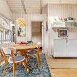 Dining area with round table and chairs, wall shelf and fireplace. Wooden walls and floor.