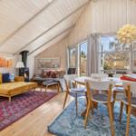 Living and dining area with wooden ceiling, sofa, dining table, and windows.