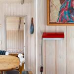 Dining area with round table and white chairs, wall with artwork and red wall lamp.