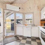 Kitchen with white cabinets, sink, and stove. Wooden walls and tiled floor. Door leads outside.