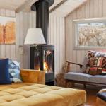 A room with fireplace, sofa, and window. Wall art and cushions are visible.