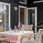 Terrace with table, chairs, and grill. Table set with bottle and glasses.