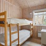 A bedroom with wooden walls and bunk bed. Window and dresser are visible.