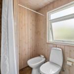 Bathroom with wooden walls, toilet, bidet, and shower with curtain.