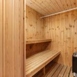 Sauna with wooden walls, bench, and floor. Wooden box with firewood.