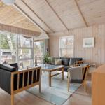 Living room with wooden walls, sofa, table, and windows to terrace.