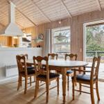 Kitchen and dining area with wooden ceiling, table and chairs, windows to the terrace.