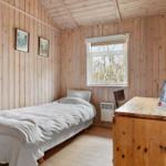 A bedroom with wooden walls, a bed, and a desk with a chair.
