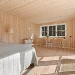 Bedroom with bed, desk, and window. Wooden walls and floor.