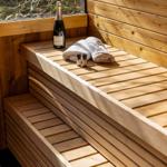 Wood sauna with bench, bottle, and towels. Window shows forest.