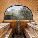Sauna with wooden benches and round window view of forest