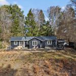 Black cabin with terrace in the woods. Garden area with lounge chairs.