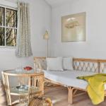 A room with rattan sofa, table, and window overlooking trees.