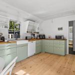 Kitchen with light green cabinets, wooden surfaces, and modern appliances.