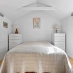 Bedroom with sloped ceiling, two windows, and a bed with white bedding.