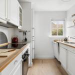 Kitchen with white cabinets, wooden countertops, and window to the garden.