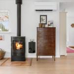 Wood-burning stove, wooden chest, and window with view to outdoors.