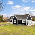 Black wooden house with white trim and garden. Backyard with terrace and umbrella.