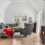 Living room with sofa, armchair, fireplace, and wooden floor.