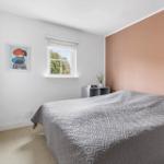 Bedroom with bed, window, and rose-toned wall.