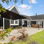 Black wooden house with patio, garden, and umbrella. Wooden tables and chairs.