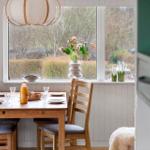 Dining table with chairs by window with flowers and landscape.