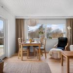 Living and dining area with wooden furniture, windows, and terrace door.