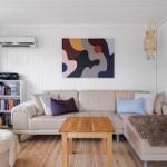 Living room with sofa, coffee table, and wall art. Wooden floor and white walls.