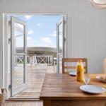 Dining area with table, chairs, and view of balcony overlooking landscape.